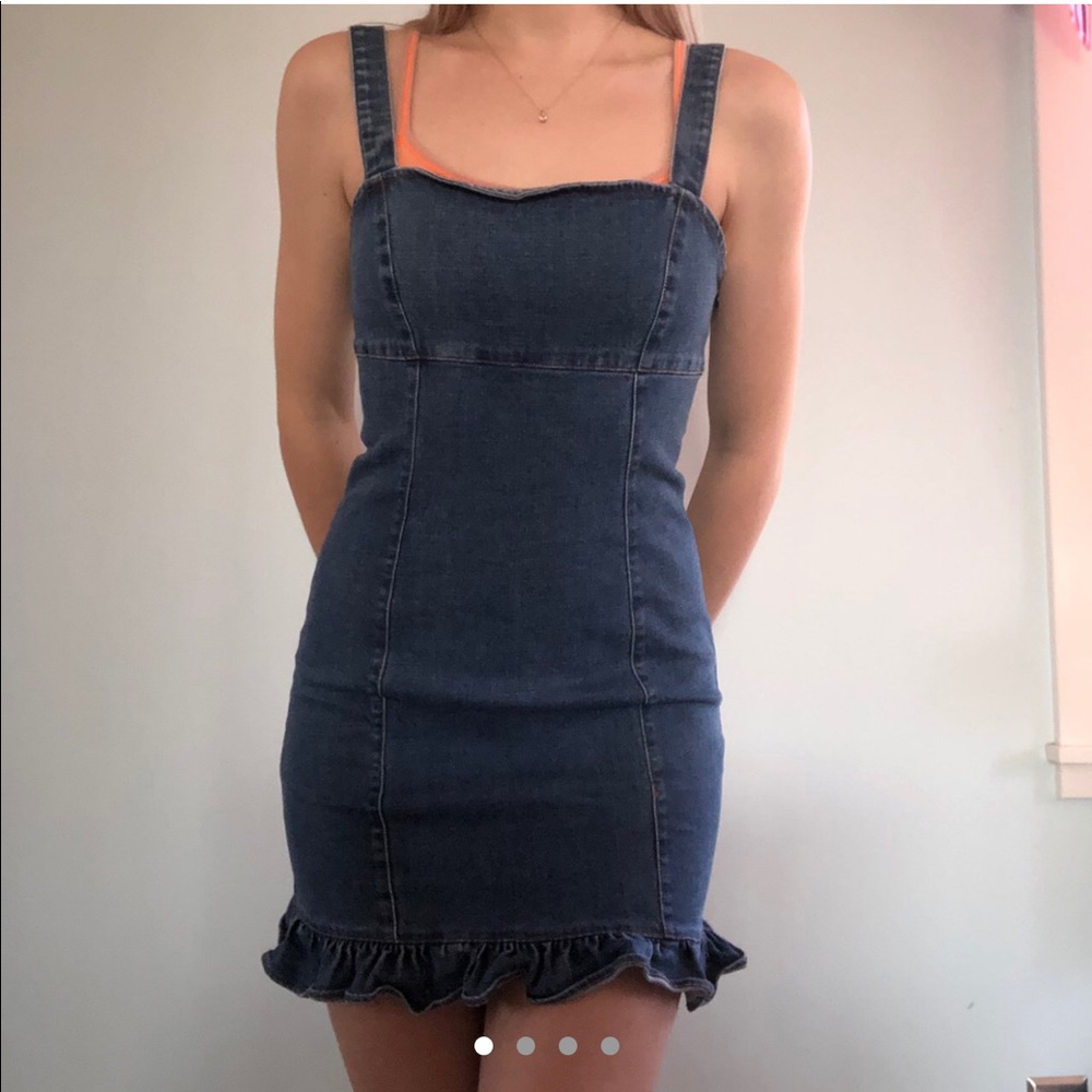 Denim dress with brown stitching and ruffle trim.